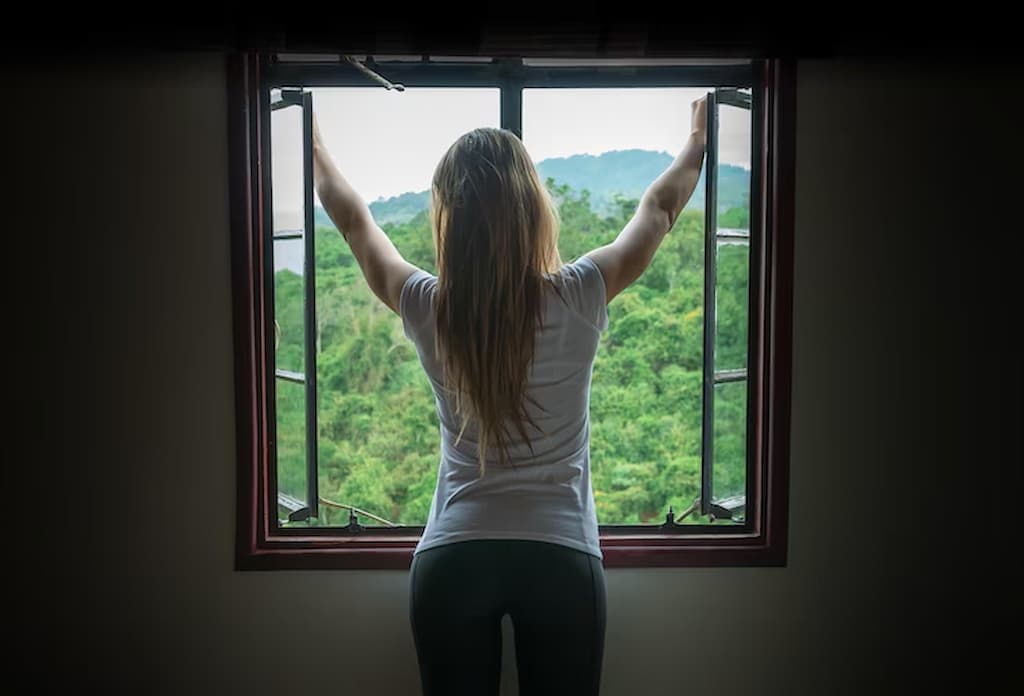 mujer abriendo ventanas para ventilar casa